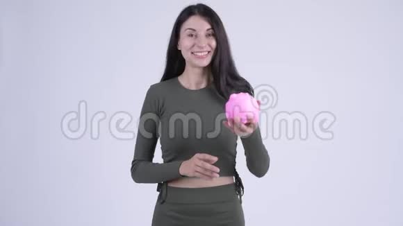 快乐的年轻美丽的女人手里拿着储蓄罐竖起大拇指视频的预览图