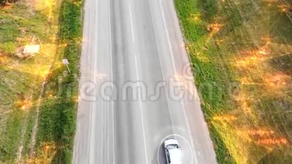 从无人驾驶飞机上方的汽车在阳光明媚的日子沿着空旷的乡村道路行驶未来主义技术视频的预览图
