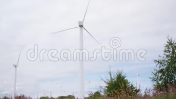 人类在风力涡轮机能源生产的背景下穿过田野中弹视频的预览图
