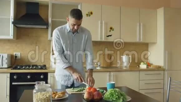 英俊的年轻人做素食早餐在家厨房切菜做沙拉视频的预览图