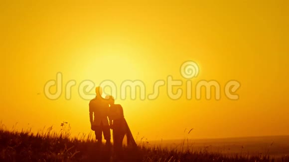 可爱的一对年轻的男人和美丽的女孩走在夕阳草甸剪影视频的预览图
