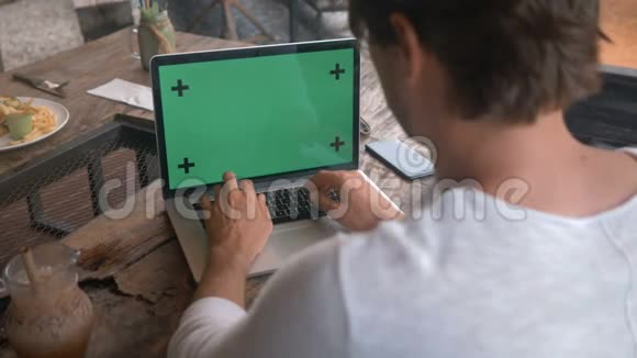 在咖啡厅用绿色屏幕的笔记本电脑上工作的男性双手特写视频的预览图