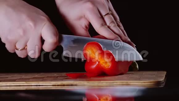 成熟的红椒女手特写刀切割板上视频的预览图