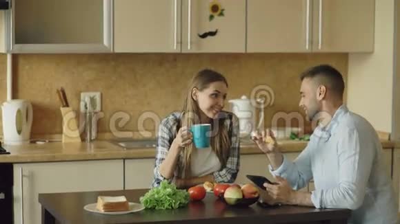 有魅力的夫妇在厨房里聊天和吃早餐视频的预览图