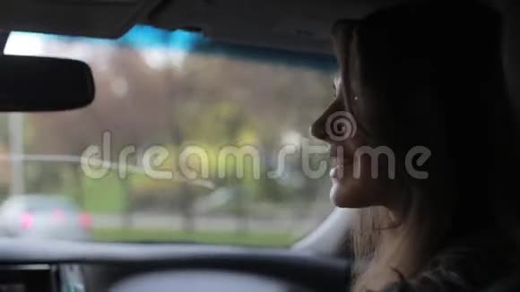 秋天一个漂亮的年轻女人在一个城市里开车她说着笑看着车窗外视频的预览图