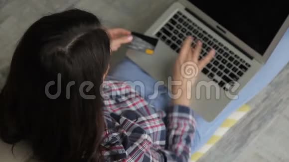 年轻的黑发女郎用银行卡在网上商店购买视频的预览图
