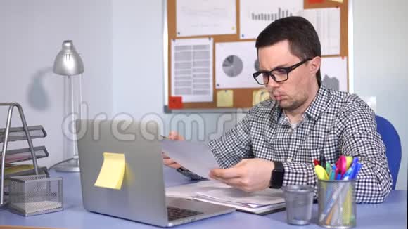 忙碌的人在工作场所填写纸质表格看着笔记本电脑显示器视频的预览图
