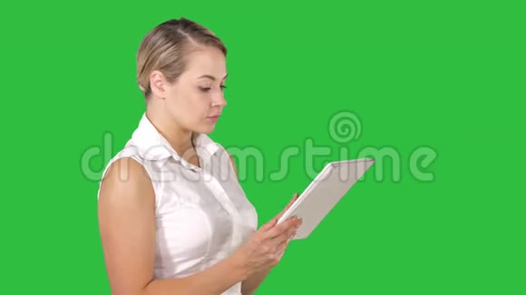 漂亮的女人站在绿色屏幕上使用平板电脑Chroma键视频的预览图