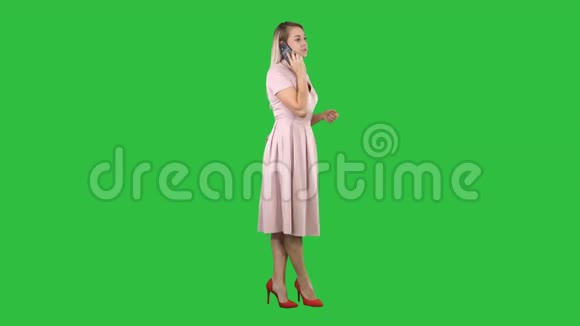 漂亮的女孩穿着粉红色的裙子在电话上的绿色屏幕Chroma键视频的预览图