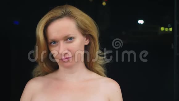一个没有化妆的年轻女人的肖像裸露的肩膀抵着城市模糊的灯光复制空间视频的预览图
