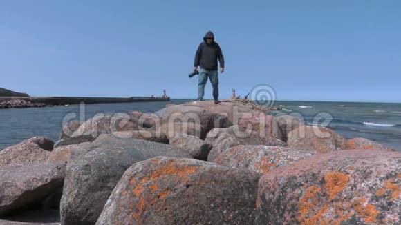 摄影师独自走在海边的石墩上视频的预览图
