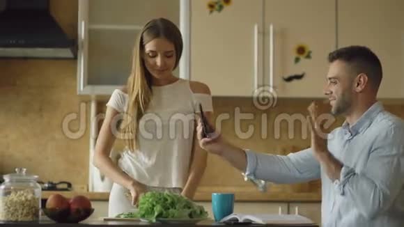 有魅力的一对夫妇在厨房里清晨做饭用平板电脑在线视频聊天视频的预览图