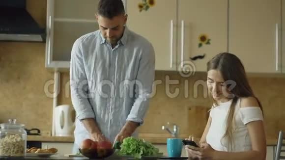 一对漂亮的夫妇一大早就在厨房里美女与男友分享智能手机社交媒体视频的预览图