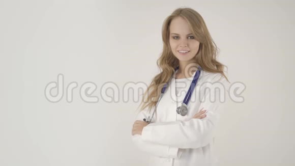 年轻微笑的女医生双臂交叉在白色背景上视频的预览图