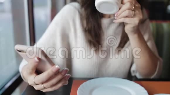 一个女人在咖啡馆喝茶用手机社交和电子邮件晚餐和网页浏览视频的预览图