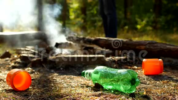 在前景的林间空地上有塑料瓶的垃圾火在冒烟人们走在里面视频的预览图