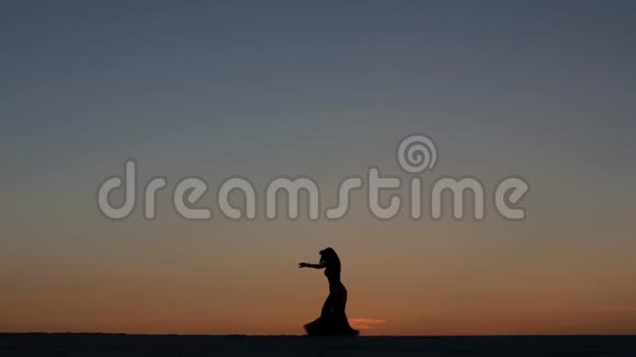 舞者在一片炽热的夕阳背景下在沙滩上进行性舞剪影式视频的预览图
