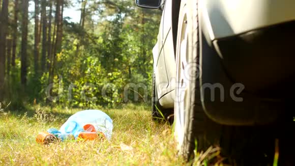 一个蓝色的袋子里装着塑料瓶的垃圾躺在汽车附近的大自然上塑料垃圾污染了大自然视频的预览图