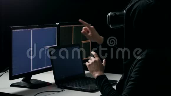 虚拟现实头盔中的黑客在黑暗的房间里工作人程序员获得使用VR头套的经验视频的预览图