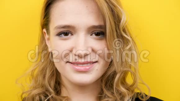 黄色背景下美丽的年轻女子对着镜头微笑视频的预览图