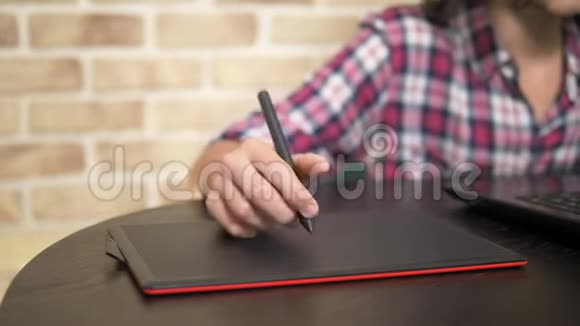 差不多了一个穿格子衬衫的少年用手写笔的手在图形平板电脑上工作视频的预览图