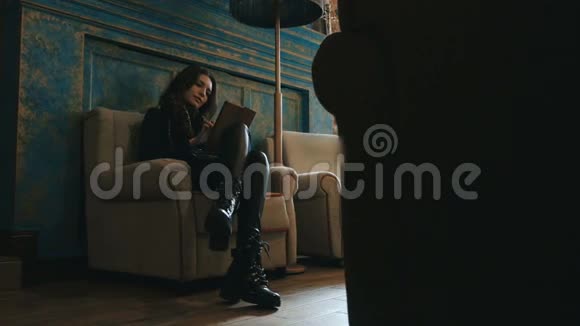 一个妩媚的黑发女人坐在椅子上手里拿着一块平板电脑的画像视频的预览图