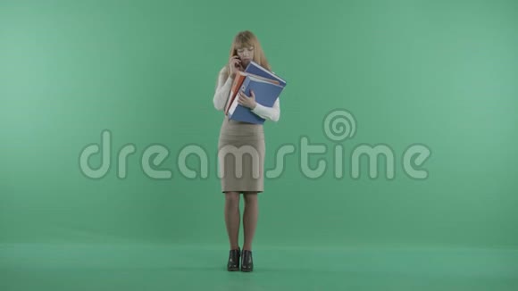 一个年轻的女人拿着一堆文件在电话里说话视频的预览图