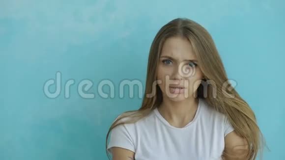 愤怒的年轻女子在蓝色背景上紧张地看镜头的肖像视频的预览图