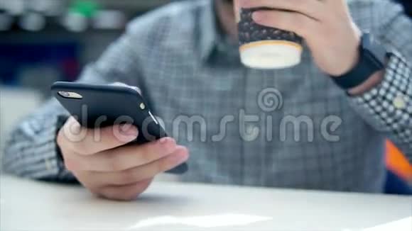 用手机和塑料杯喝咖啡的男人手的特写镜头视频的预览图
