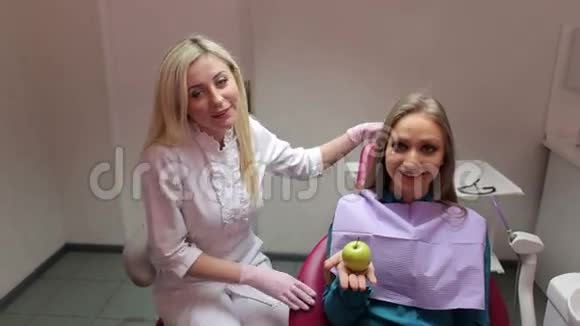 一个女孩和牙医在牙科办公室用绿苹果的肖像视频的预览图