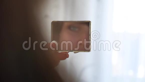一个漂亮的年轻女孩照镜子在室内看到一只倒影美丽的眼睛美丽的概念视频的预览图