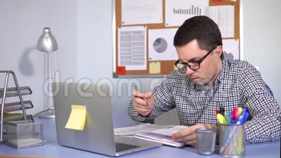办公室工作人员在笔记本电脑上工作并在文件中写下信息视频的预览图