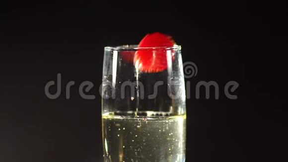 草莓在黑暗中倒在一杯香槟里视频的预览图