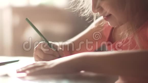 六岁的孩子坐在一张桌子旁画房子清晨阳光下的小女孩视频的预览图