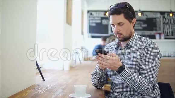 穿着休闲装的人坐在咖啡馆里他用他的智能手机视频的预览图