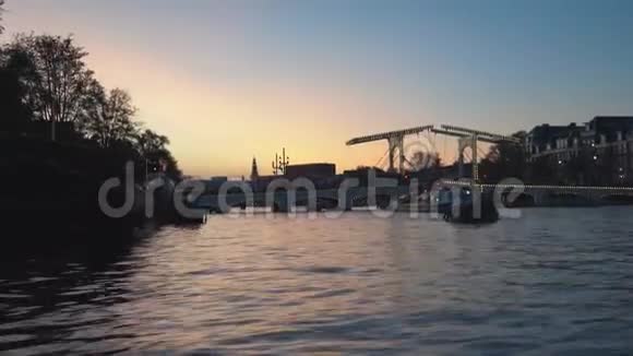阿姆斯特丹的夜景由照明建筑和路灯装饰的运河经过桥下的船只视频的预览图