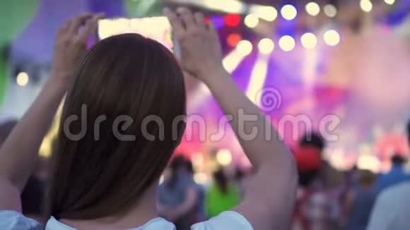 露天摇滚音乐会的人群聚会女人站着手里拿着智能手机拍摄视频视频的预览图