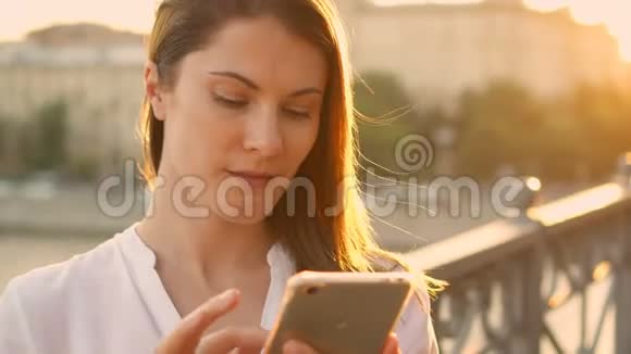 快乐的年轻女人在户外放松漂亮的女孩在她的智能手机上聊天夏日阳光灿烂视频的预览图