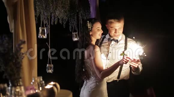 新婚夫妇在户外燃烧孟加拉灯微笑的新郎和新娘用爱看着对方闭上眼睛视频的预览图
