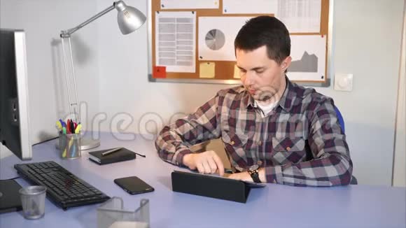 一个男人在工作休息时正在平板电脑上和他的朋友聊天视频的预览图
