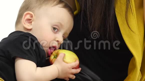 小孩子吃苹果挨着妈妈白色背景慢动作关门视频的预览图