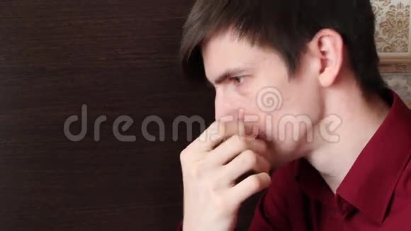 一个穿红色衬衫的年轻人用手指摸着他的脸看上去很兴奋视频的预览图