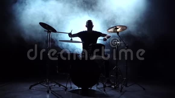 鼓手在鼓上大力演奏旋律黑色背景剪影慢动作视频的预览图