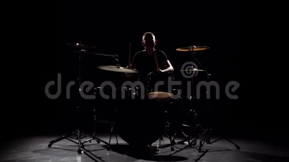 职业音乐家用棍子在鼓上演奏音乐黑色背景剪影慢动作视频的预览图