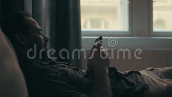 年轻人用手机躺在沙发上视频的预览图