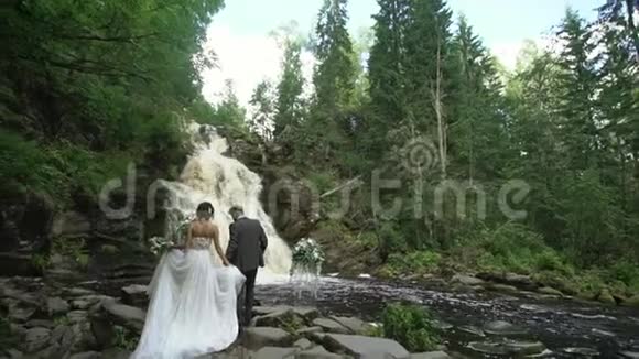 年轻的新婚夫妇在瀑布附近举行婚礼视频的预览图