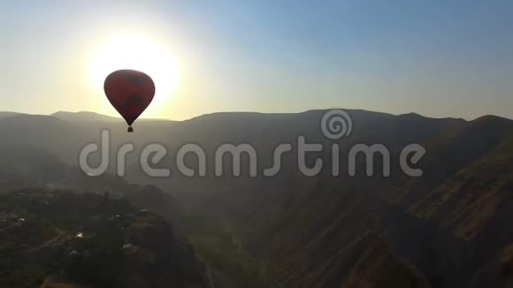 在美丽的夕阳下热气球飞过山村的空中景色视频的预览图