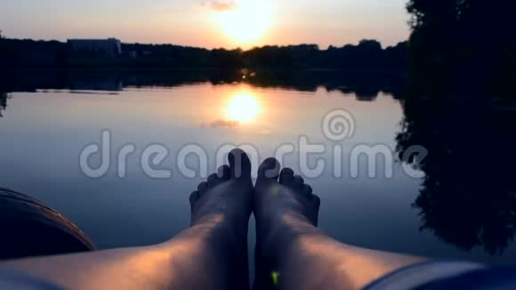双脚躺在靠近湖塘的码头上视频的预览图