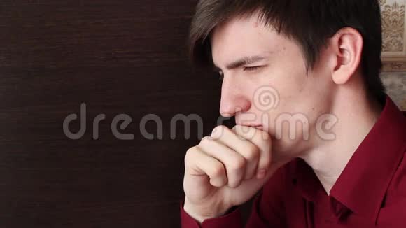 一个穿红衬衫的年轻人张扬着脸用手指捂住嘴唇视频的预览图