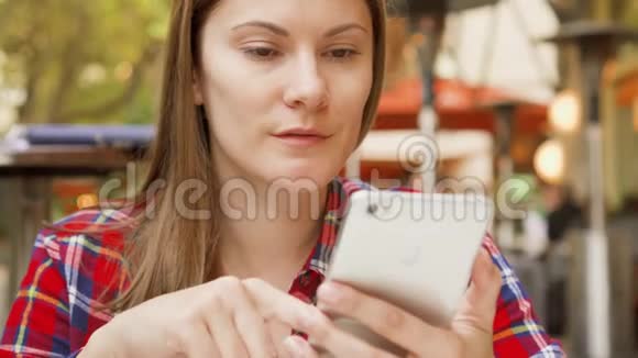坐在咖啡馆里看菜单的美女微笑的美女用手机浏览视频的预览图